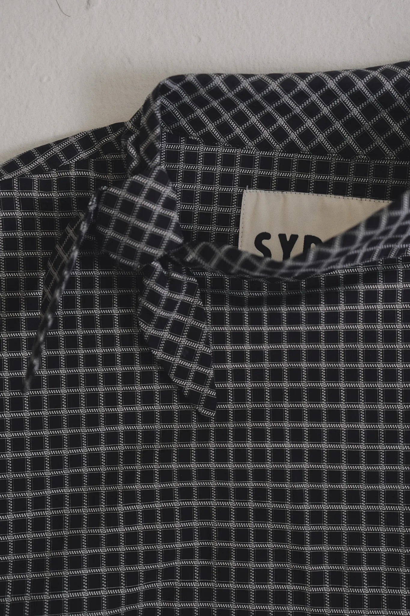 黑格領結襯衫，棉彈親膚面料右側領結與落肩短版設計，展現修長優雅比例。