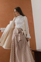 模特兒穿著燕麥白羊絨背心洋裝外套，柔軟羊絨面料搭配立體花釦、後開衩與側袋設計，展現優雅多變造型。