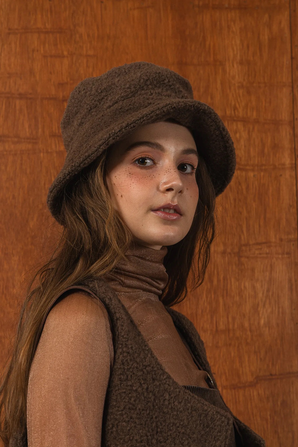 模特兒配戴手作白色羊絨鐘形帽，喀什米爾面料與硬挺帽緣，呈現溫潤質感與修飾臉型的秋冬造型。