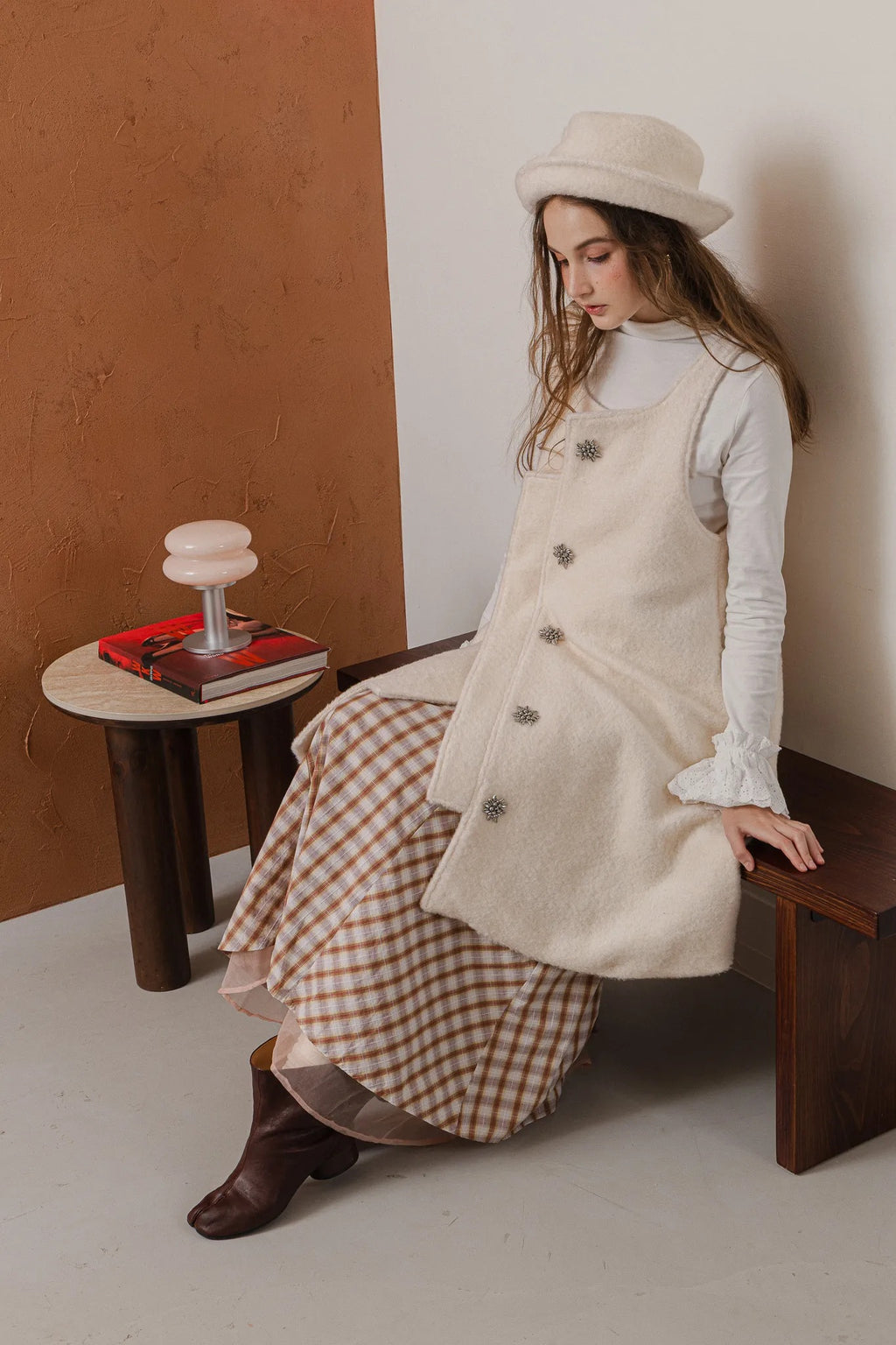 模特兒配戴手作白色羊絨鐘形帽，喀什米爾面料與硬挺帽緣，呈現溫潤質感與修飾臉型的秋冬造型。