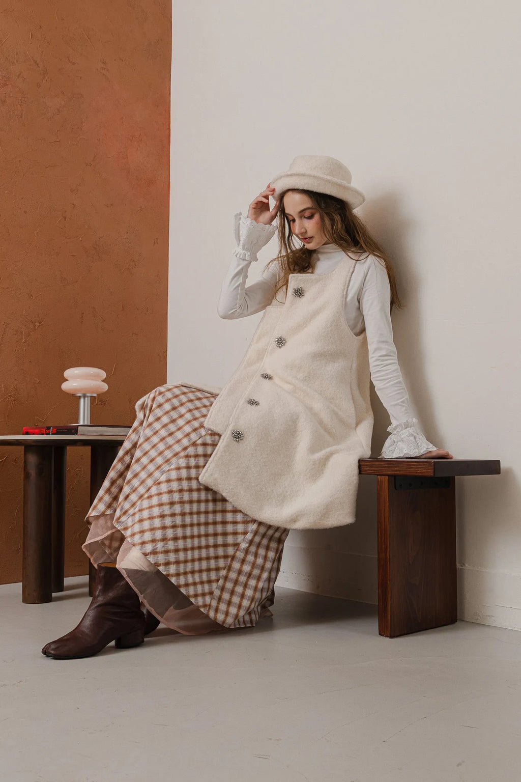 模特兒配戴手作白色羊絨鐘形帽，喀什米爾面料與硬挺帽緣，呈現溫潤質感與修飾臉型的秋冬造型。