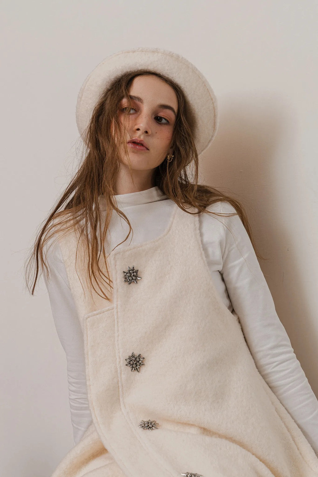 模特兒配戴手作白色羊絨鐘形帽，喀什米爾面料與硬挺帽緣，呈現溫潤質感與修飾臉型的秋冬造型。