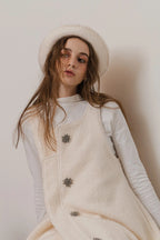 模特兒配戴手作白色羊絨鐘形帽，喀什米爾面料與硬挺帽緣，呈現溫潤質感與修飾臉型的秋冬造型。