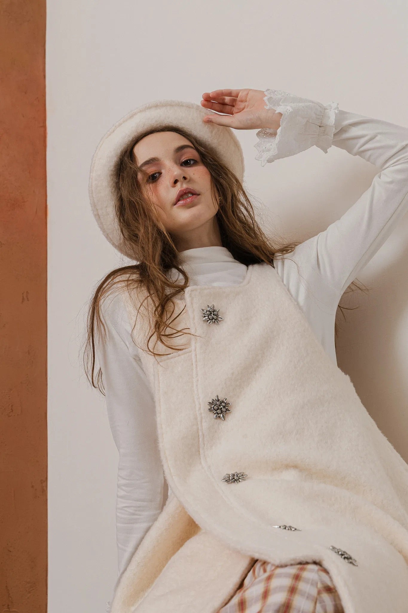 模特兒配戴手作白色羊絨鐘形帽，喀什米爾面料與硬挺帽緣，呈現溫潤質感與修飾臉型的秋冬造型。