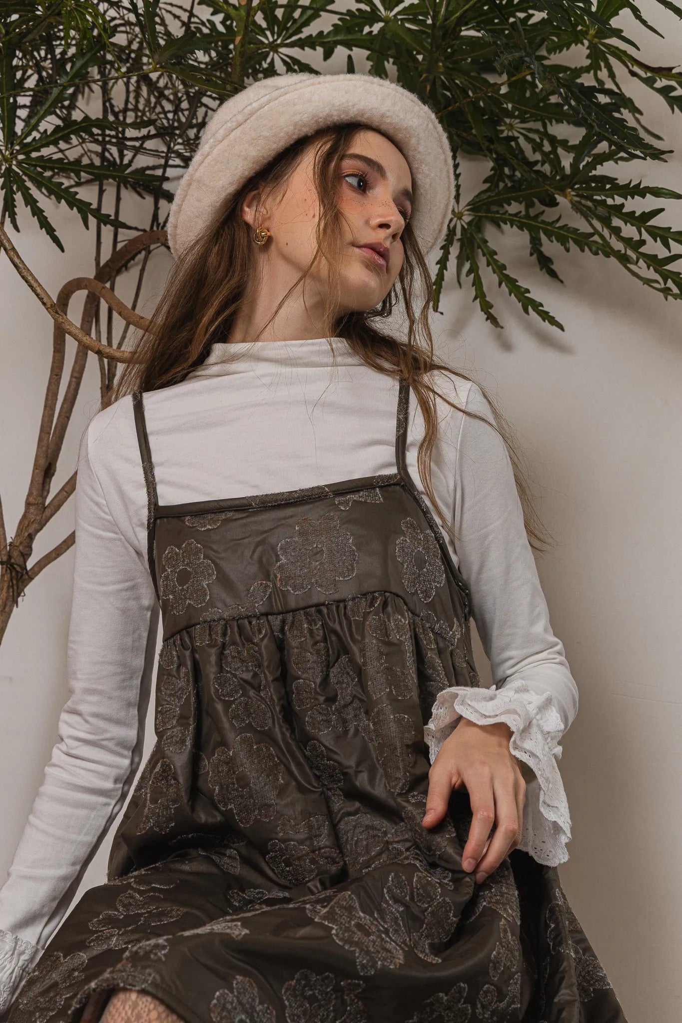 模特兒配戴手作白色羊絨鐘形帽，喀什米爾面料與硬挺帽緣，呈現溫潤質感與修飾臉型的秋冬造型。