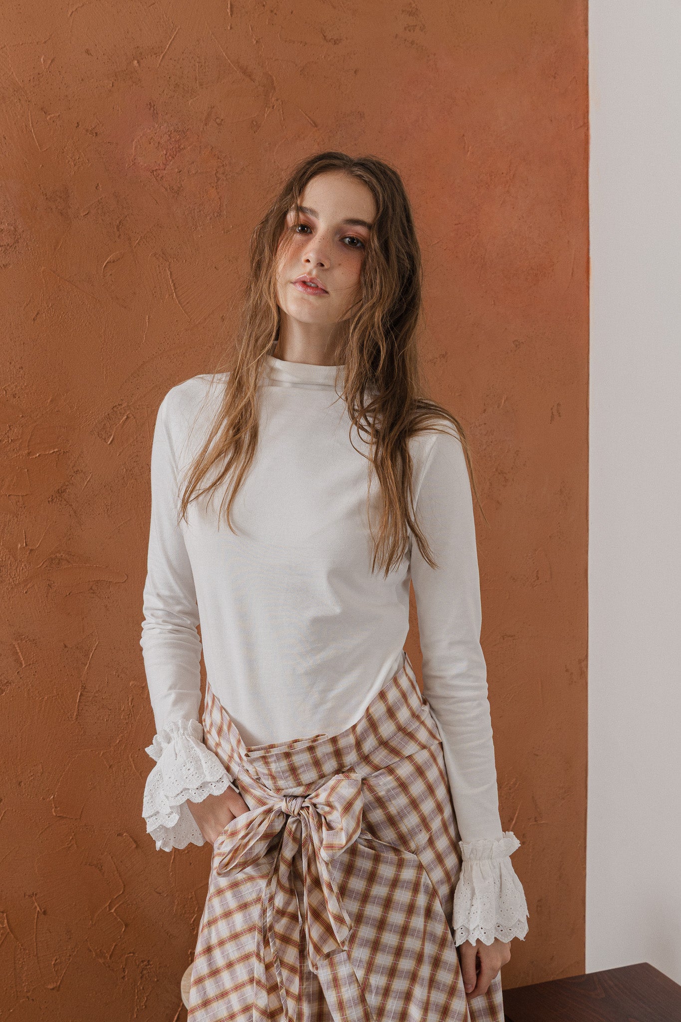 模特兒穿著清晨白蕾絲裝飾袖上衣，毛感面料質地柔軟舒適，袖口蕾絲細節為日常造型增添優雅儀式感。