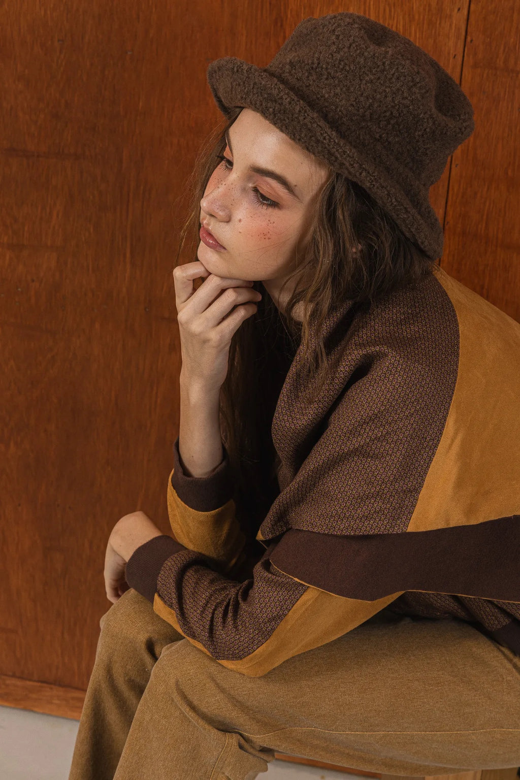 模特兒穿著拼接上衣披肩款，衣服為橘色與棕色拼接、多層次造型，呈現溫暖且有設計感的穿搭風格。