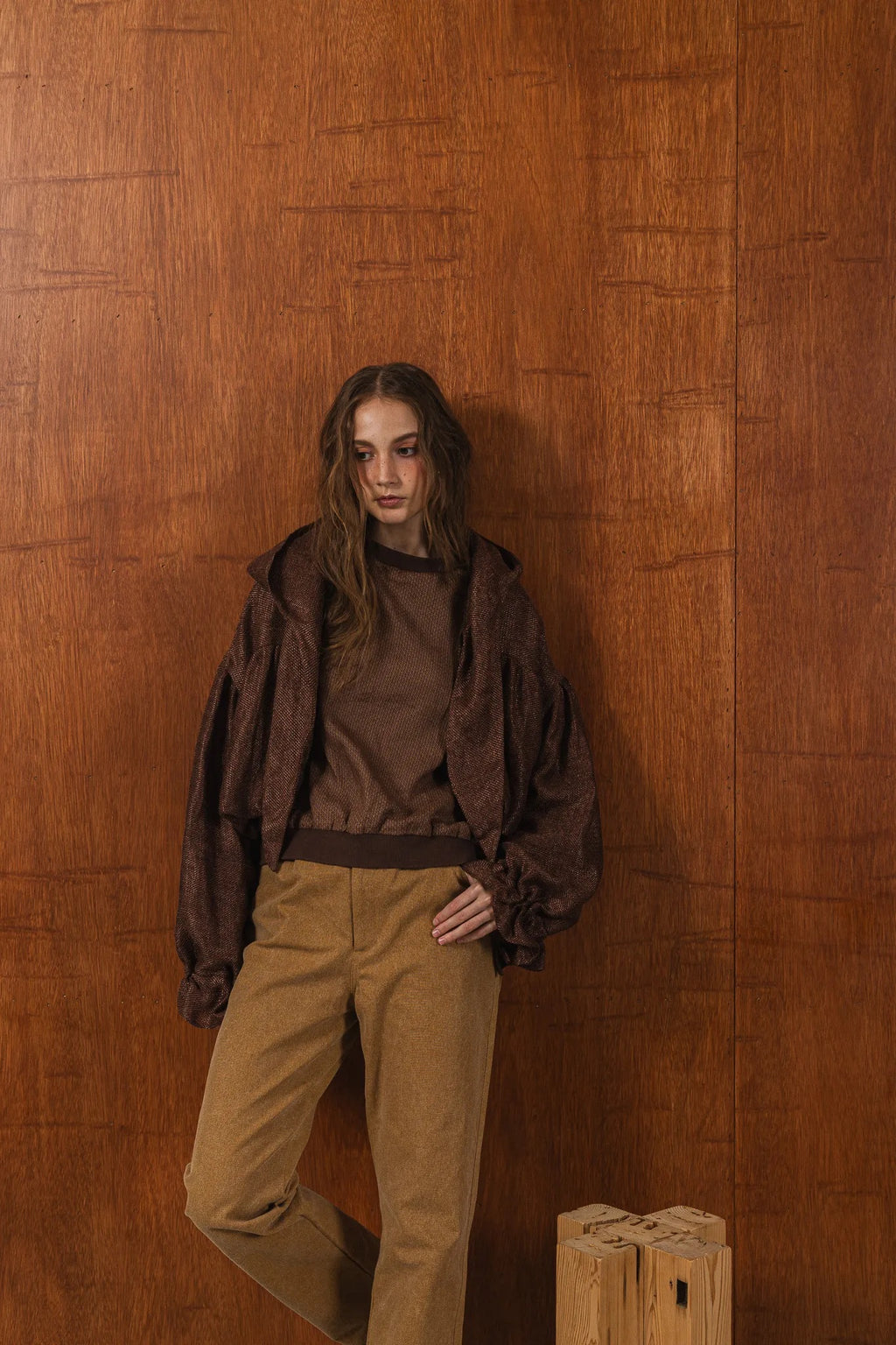 模特兒穿著拼接上衣披肩款，衣服為橘色與棕色拼接、多層次造型，呈現溫暖且有設計感的穿搭風格。