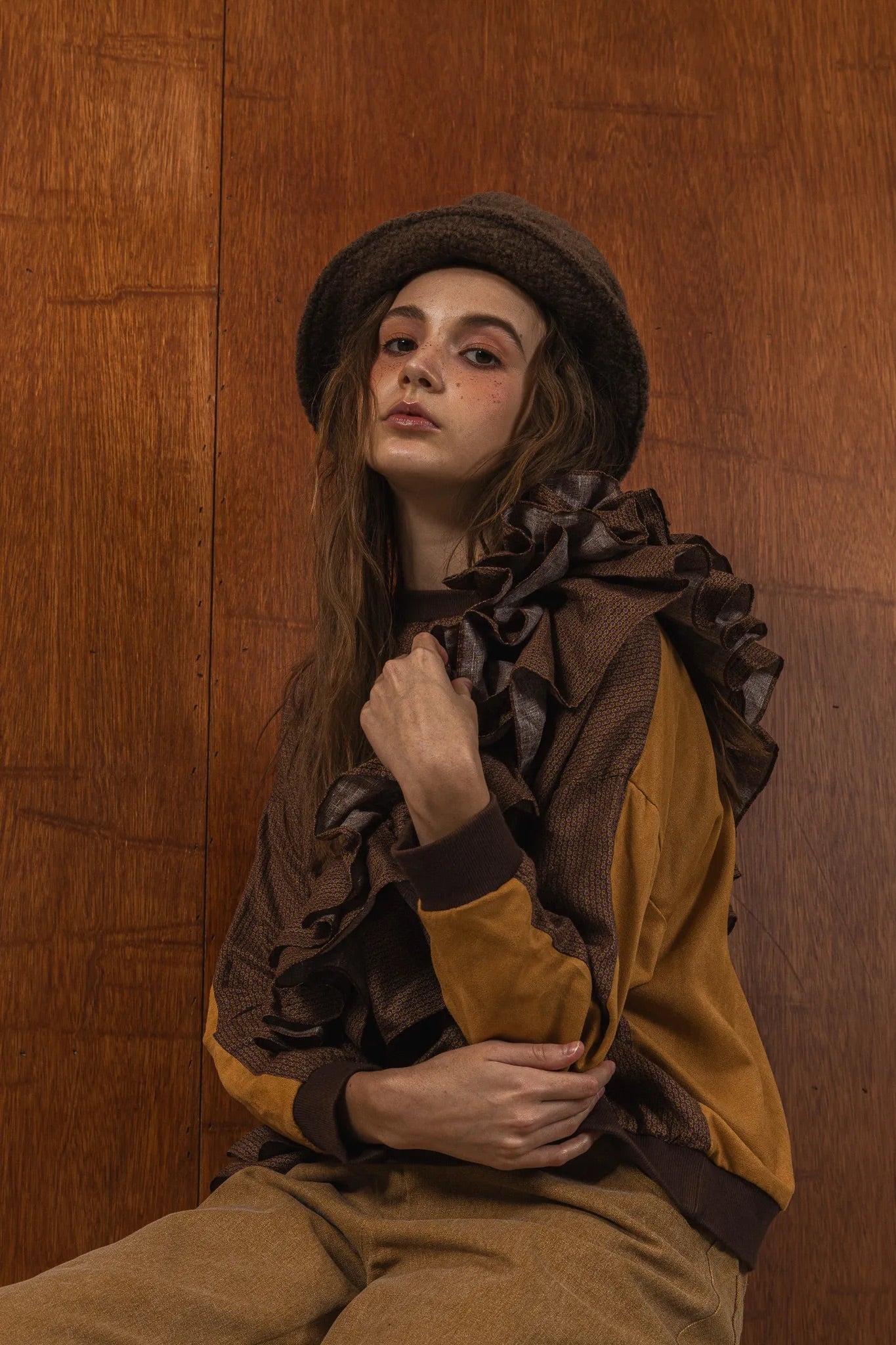 模特兒穿著拼接上衣Puff荷葉款，衣服為橘色與棕色拼接、華麗造型，呈現溫暖且有設計感的穿搭風格。