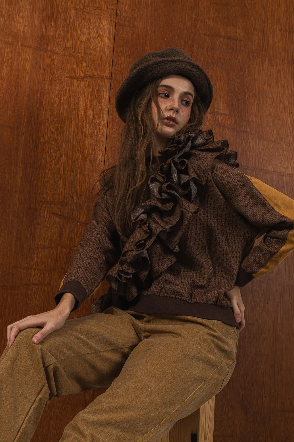 模特兒穿著拼接上衣Puff荷葉款，衣服為橘色與棕色拼接、華麗造型，呈現溫暖且有設計感的穿搭風格。