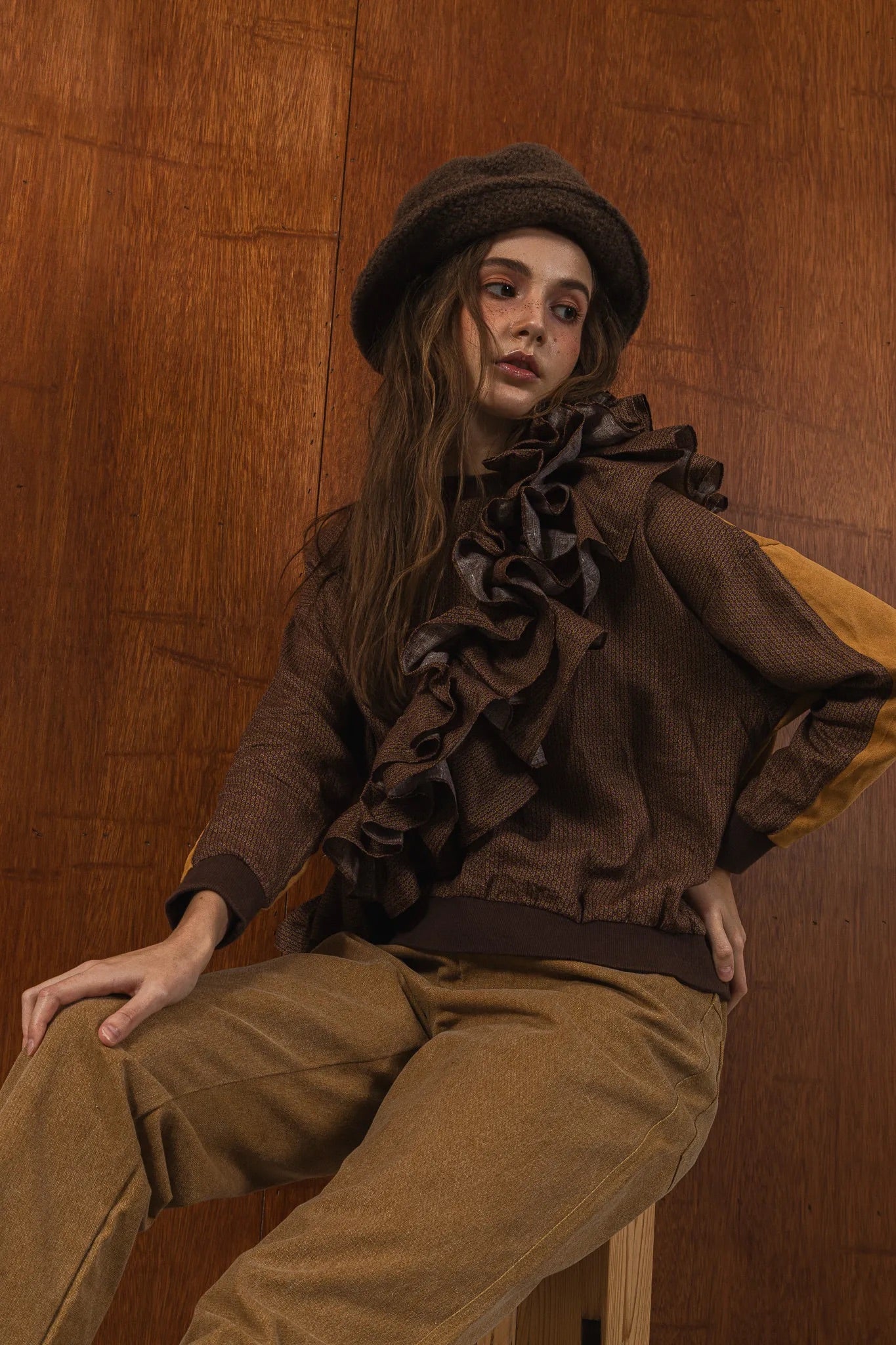 模特兒穿著拼接上衣Puff荷葉款，衣服為橘色與棕色拼接、華麗造型，呈現溫暖且有設計感的穿搭風格。