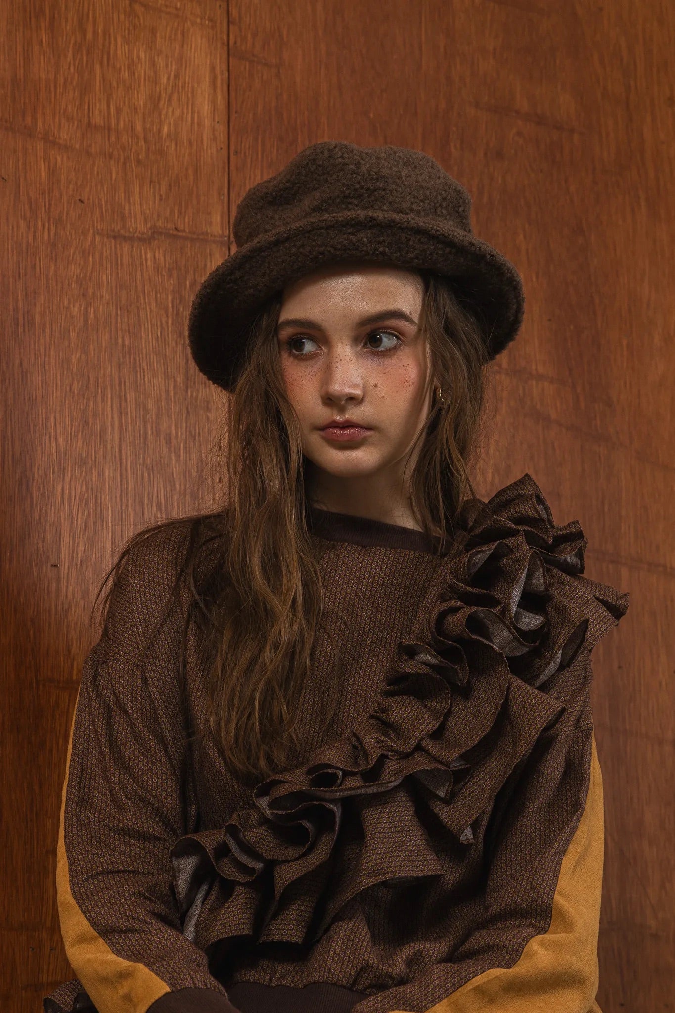 模特兒穿著拼接上衣Puff荷葉款，衣服為橘色與棕色拼接、華麗造型，呈現溫暖且有設計感的穿搭風格。