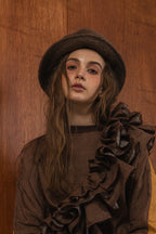 模特兒穿著拼接上衣Puff荷葉款，衣服為橘色與棕色拼接、華麗造型，呈現溫暖且有設計感的穿搭風格。