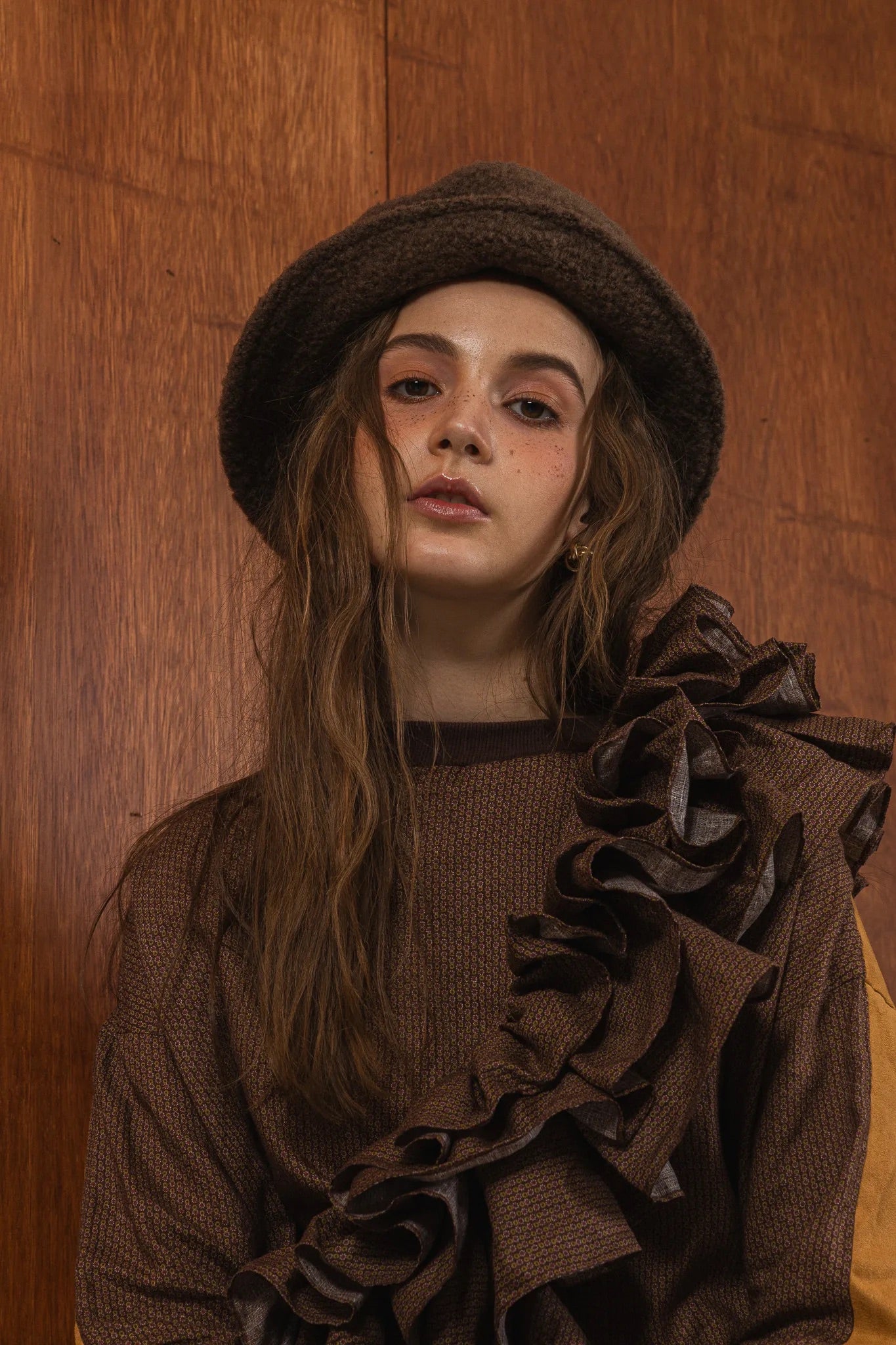 模特兒穿著拼接上衣Puff荷葉款，衣服為橘色與棕色拼接、華麗造型，呈現溫暖且有設計感的穿搭風格。