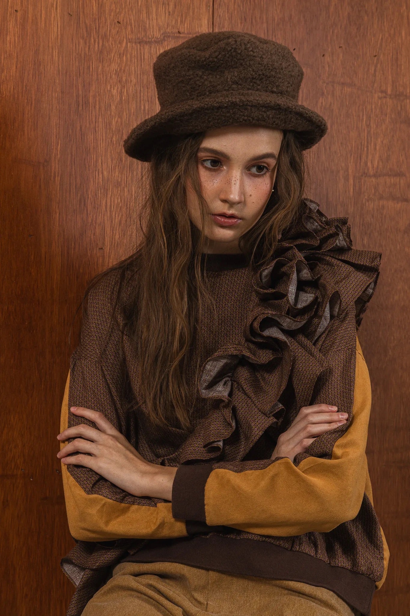 模特兒穿著拼接上衣Puff荷葉款，衣服為橘色與棕色拼接、華麗造型，呈現溫暖且有設計感的穿搭風格。