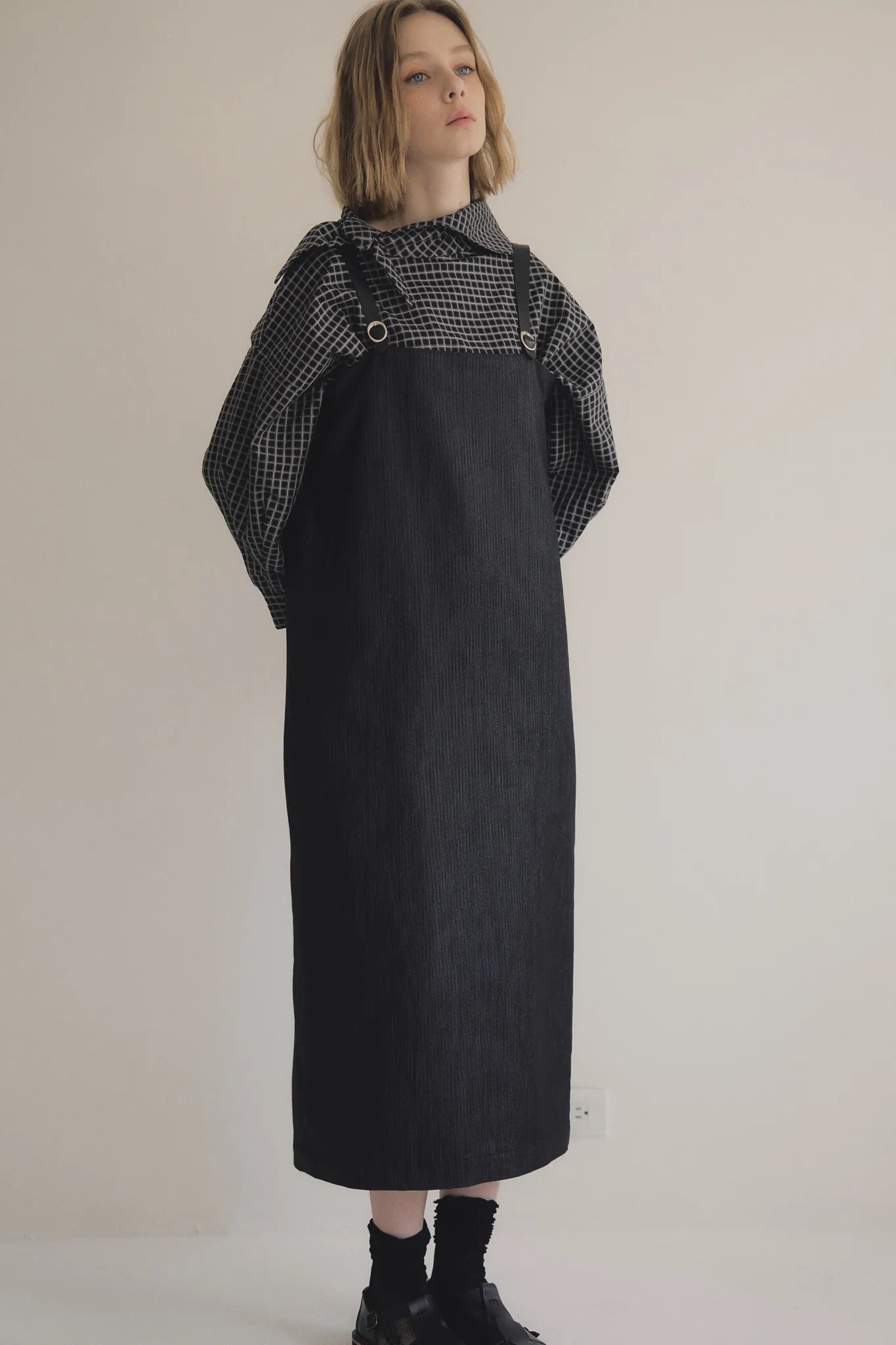 模特兒穿著光澤牛仔細肩帶洋裝，日本光澤牛仔面料搭配小牛皮細肩帶，後開衩與 H Line 剪裁，展現優雅又率性的造型。