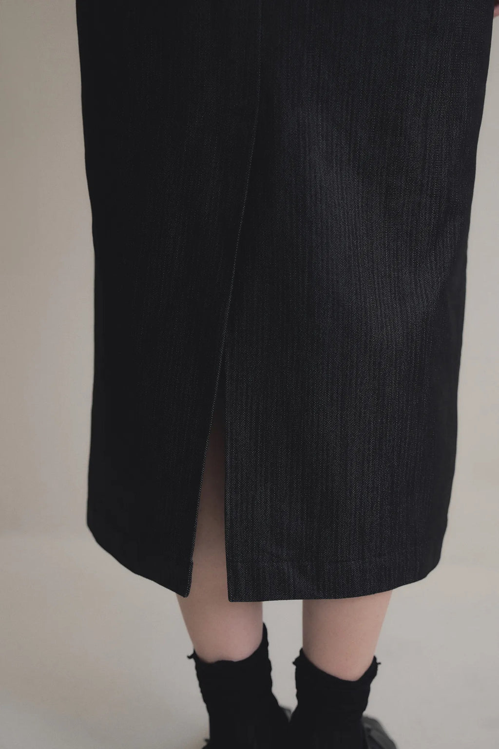 模特兒穿著光澤牛仔細肩帶洋裝，日本光澤牛仔面料搭配小牛皮細肩帶，後開衩與 H Line 剪裁，展現優雅又率性的造型。