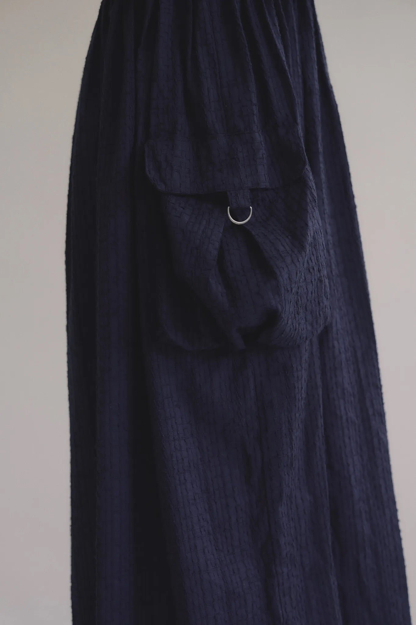 深藍肩帶雙口袋廓形洋裝，口袋細節。