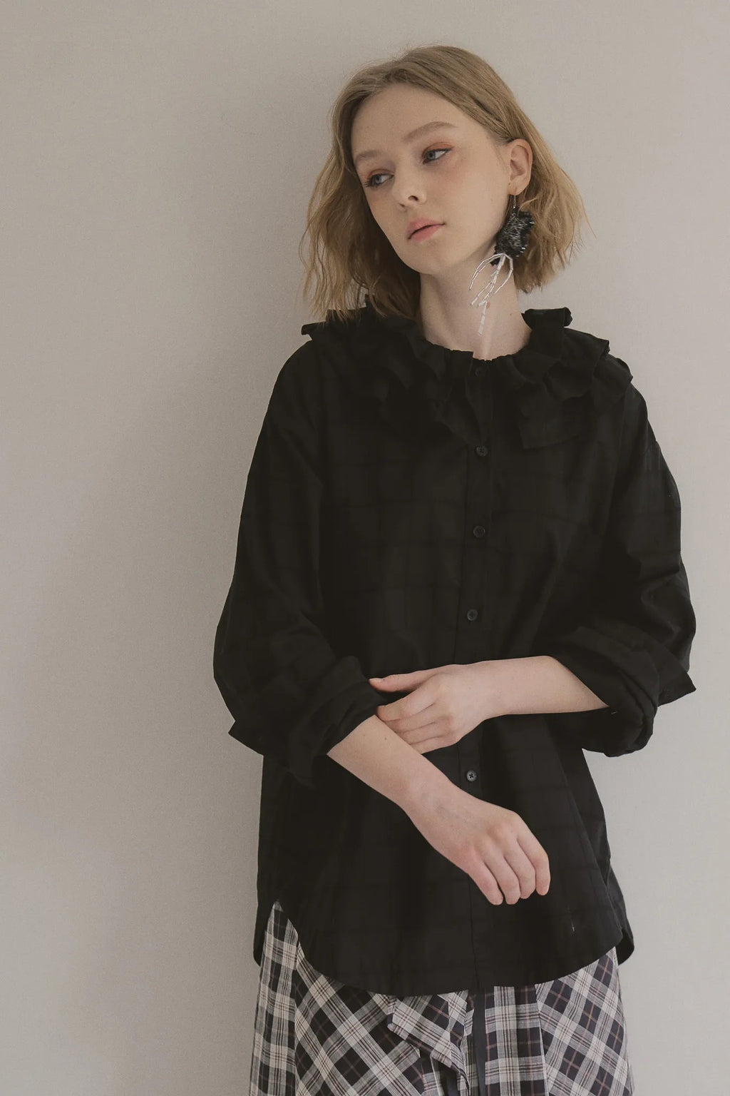 模特兒穿著黑色罌粟領設計襯衫，日本純棉親膚透氣，花瓣領口展現優雅叛逆的詩意造型。