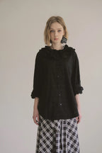 模特兒穿著黑色罌粟領設計襯衫，日本純棉親膚透氣，花瓣領口展現優雅叛逆的詩意造型。