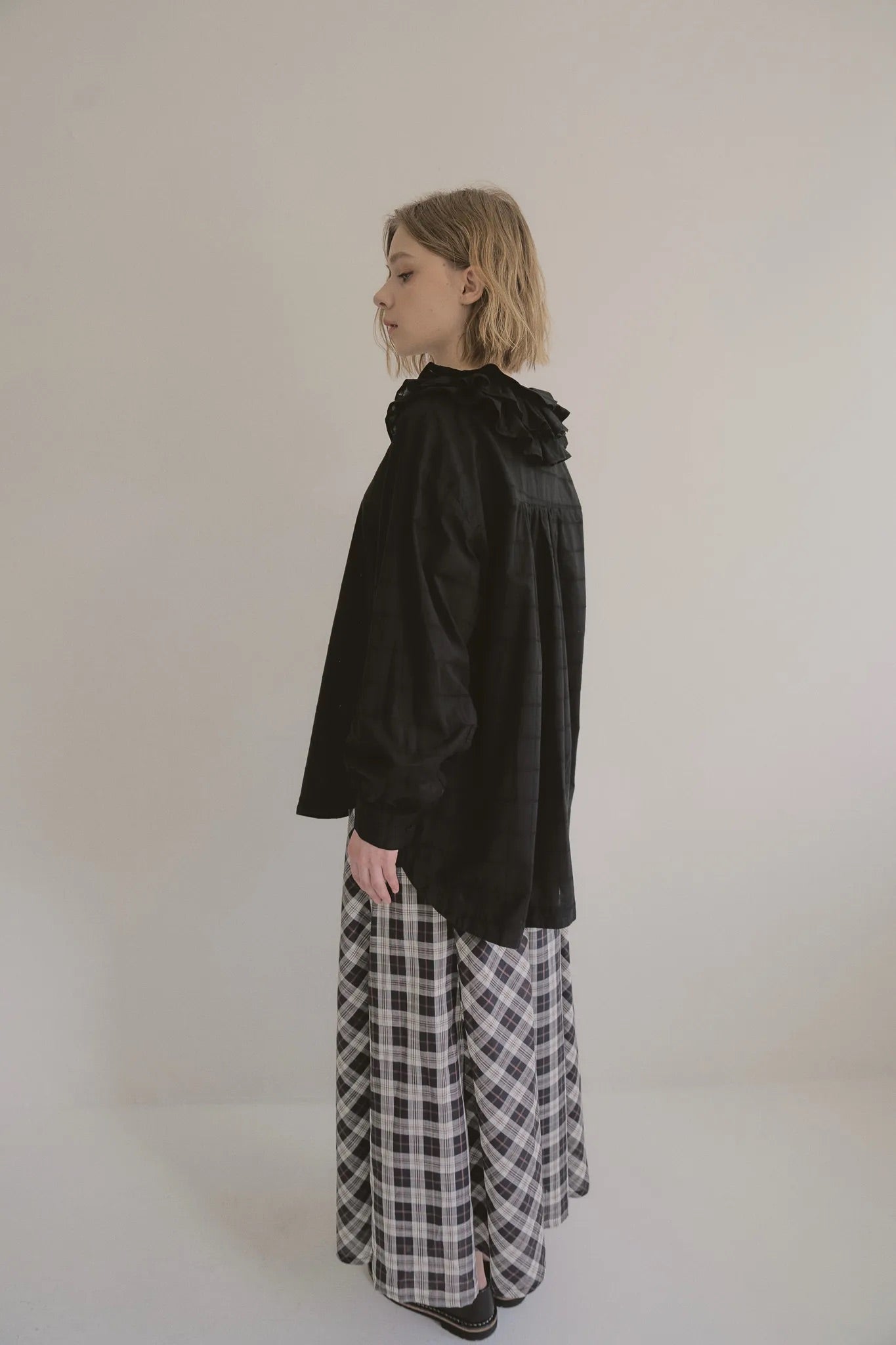 模特兒穿著黑色罌粟領設計襯衫，日本純棉親膚透氣，花瓣領口展現優雅叛逆的詩意造型。