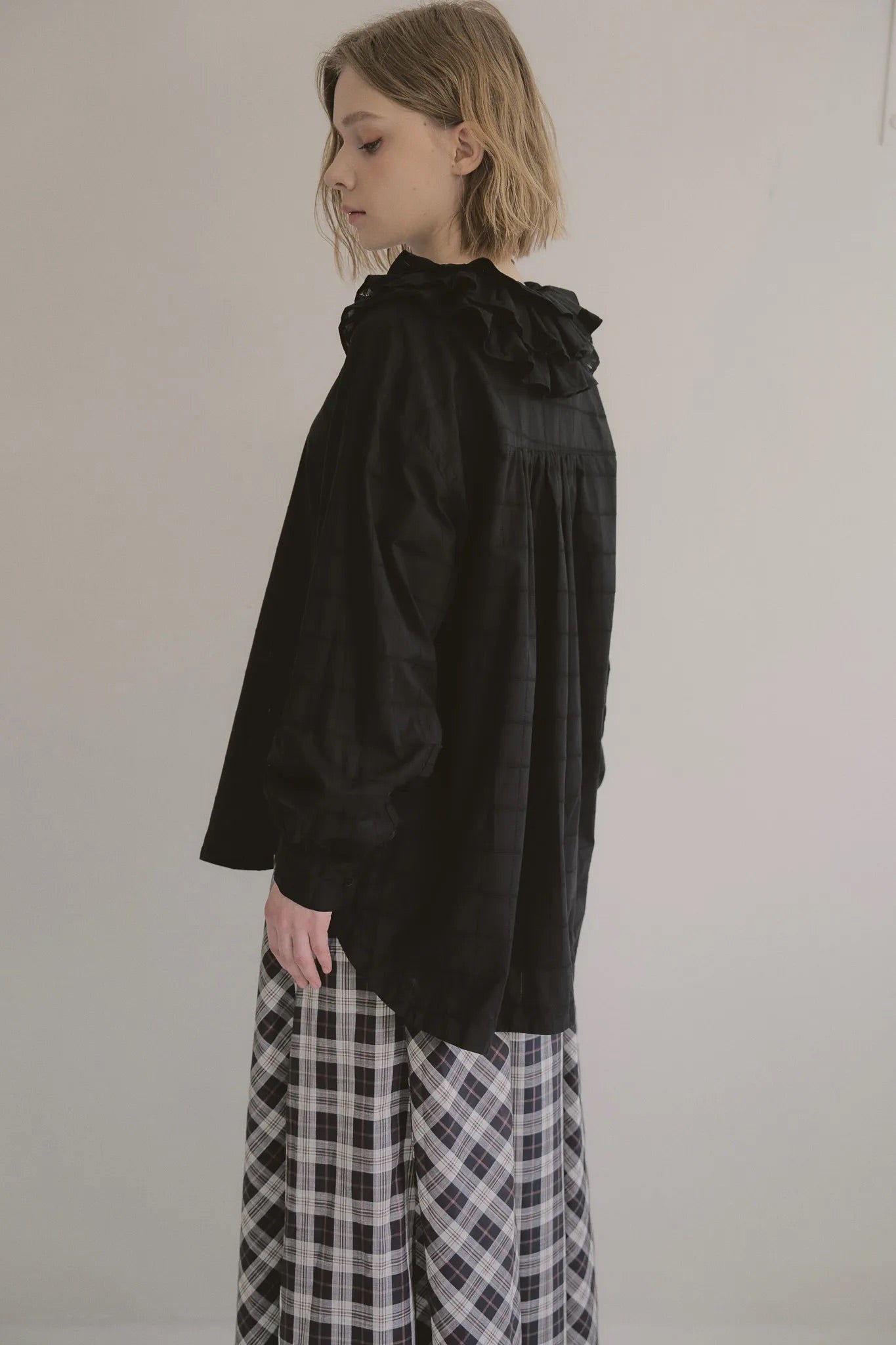 模特兒穿著黑色罌粟領設計襯衫，日本純棉親膚透氣，花瓣領口展現優雅叛逆的詩意造型。