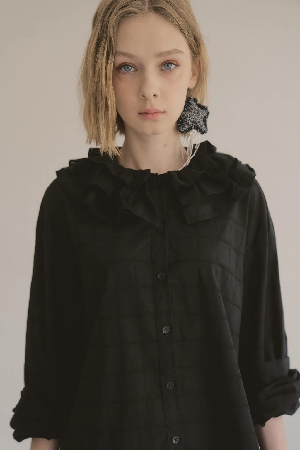 模特兒穿著黑色罌粟領設計襯衫，日本純棉親膚透氣，花瓣領口展現優雅叛逆的詩意造型。