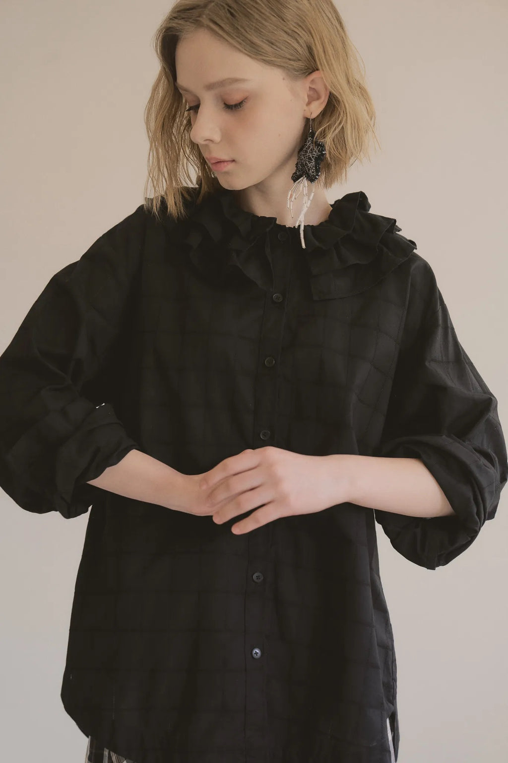 模特兒穿著黑色罌粟領設計襯衫，日本純棉親膚透氣，花瓣領口展現優雅叛逆的詩意造型。