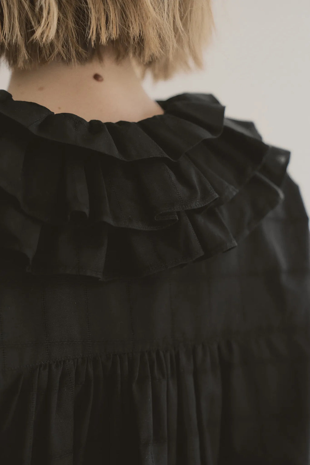 模特兒穿著黑色罌粟領設計襯衫，日本純棉親膚透氣，花瓣領口展現優雅叛逆的詩意造型。