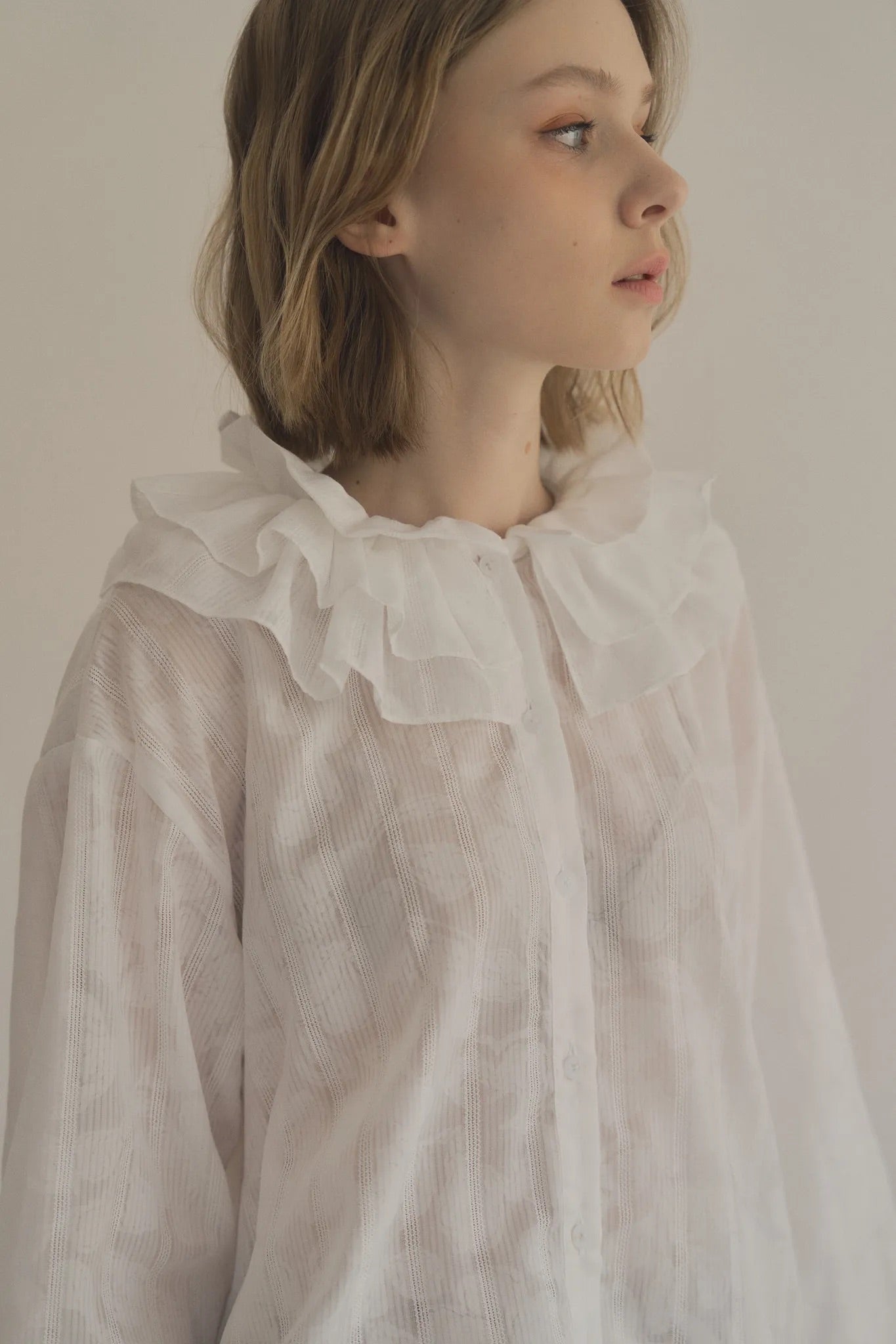 模特兒穿著白色罌粟領設計襯衫，日本純棉親膚透氣，花瓣領口展現優雅叛逆的詩意造型。