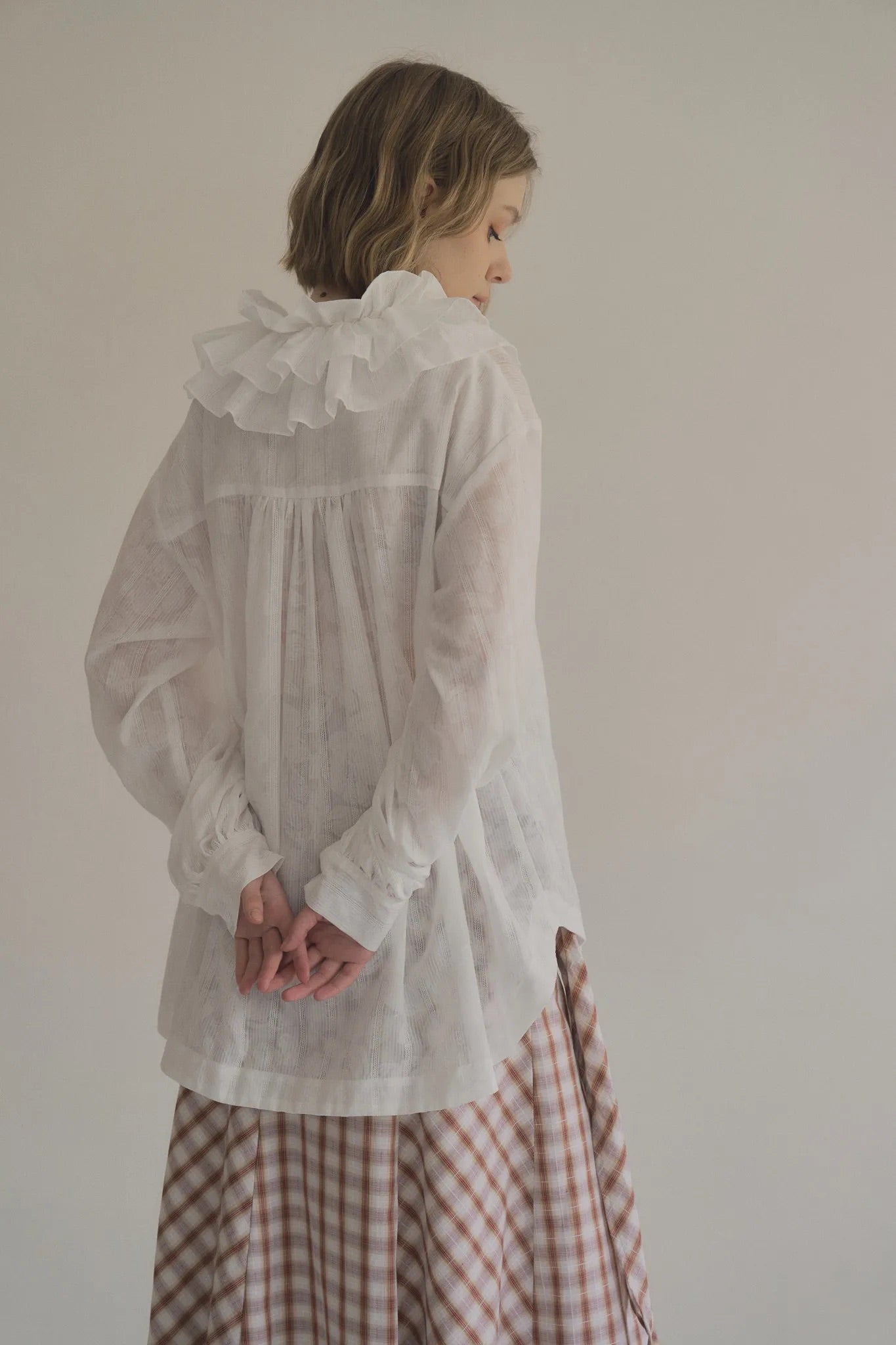 模特兒穿著白色罌粟領設計襯衫，日本純棉親膚透氣，花瓣領口展現優雅叛逆的詩意造型。