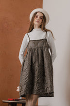 模特兒穿著羊毛花瓣細肩帶洋裝，特殊羊毛花布面料風衣質感，內裡鋪棉設計展現舒適實用的日常造型。