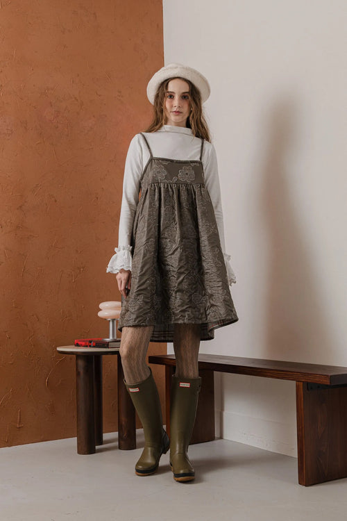 模特兒穿著羊毛花瓣細肩帶洋裝，特殊羊毛花布面料風衣質感，內裡鋪棉設計展現舒適實用的日常造型。