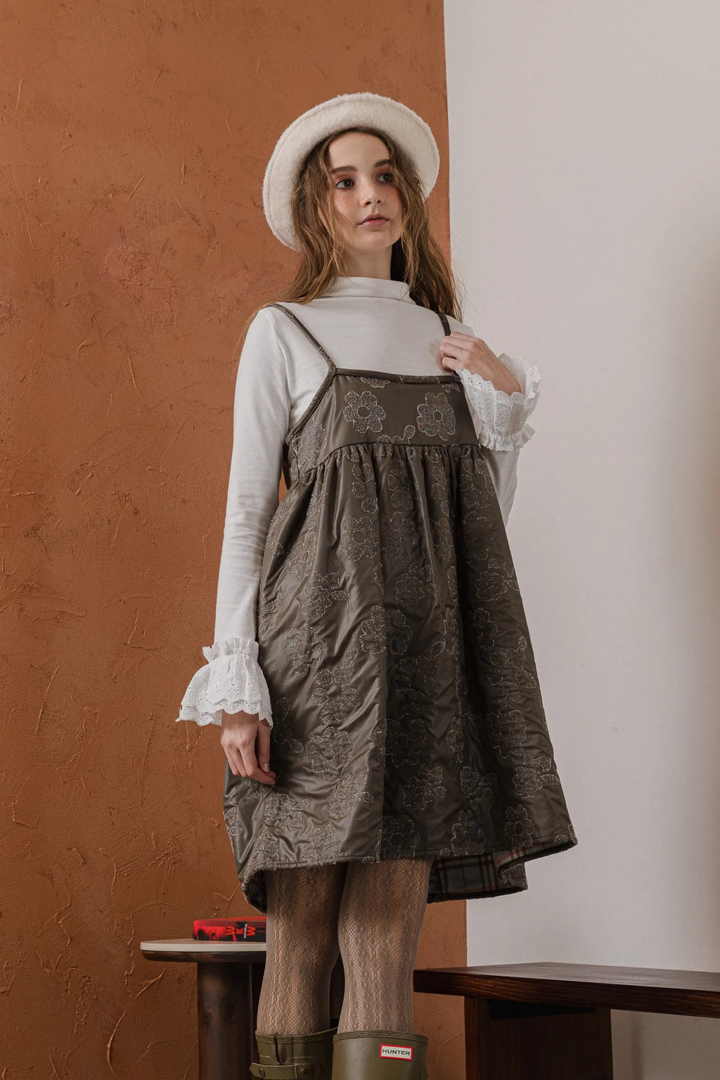 模特兒穿著羊毛花瓣細肩帶洋裝，特殊羊毛花布面料風衣質感，內裡鋪棉設計展現舒適實用的日常造型。