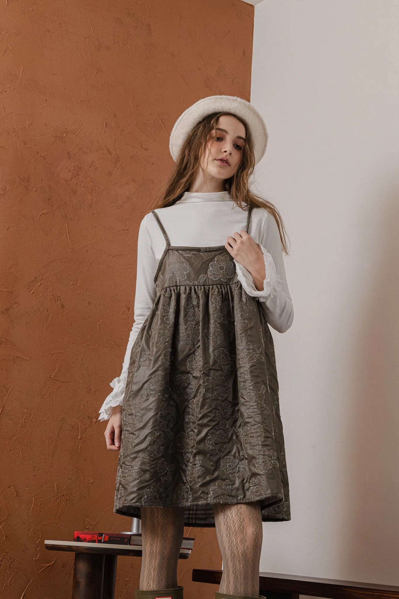 模特兒穿著羊毛花瓣細肩帶洋裝，特殊羊毛花布面料風衣質感，內裡鋪棉設計展現舒適實用的日常造型。