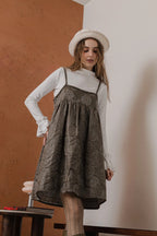 模特兒穿著羊毛花瓣細肩帶洋裝，特殊羊毛花布面料風衣質感，內裡鋪棉設計展現舒適實用的日常造型。